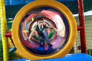 Kid,Sitting,In,Tube,On,Indoor,Playground