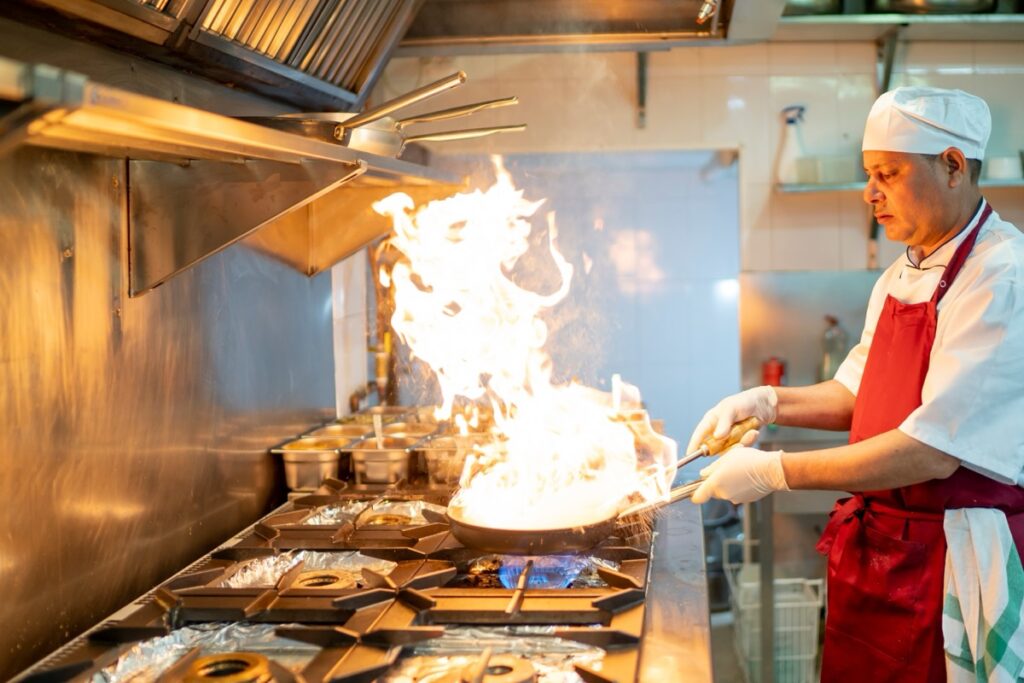 Indian,Chef,Cooking,In,Industrial,Kitchen,With,The,Burning,Pan