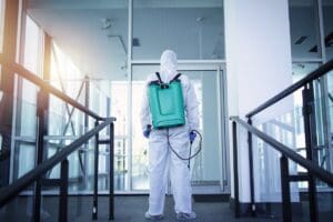 Unrecognizable person in white protection suit disinfecting public areas to stop spreading highly contagious corona virus.
