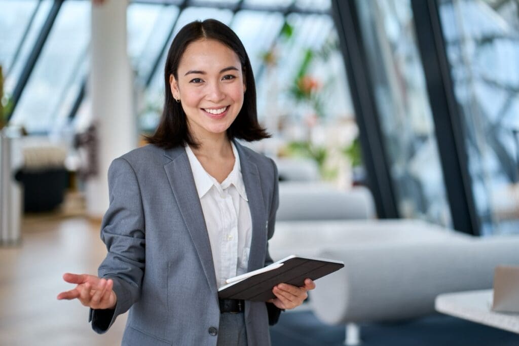 Happy,Young,Asian,Saleswoman,Looking,At,Camera,Welcoming,Client.,Smiling