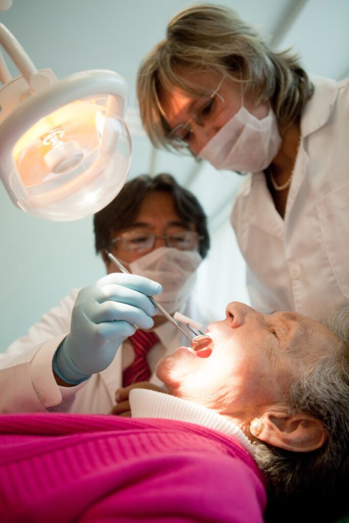 Dentist,And,His,Assistant,Working,On,And,Old,Patient