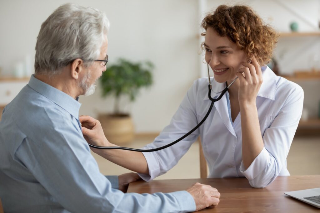 Smiling,Young,Caucasian,Female,Doctor,Hold,Stethoscope,Listen,To,Elderly