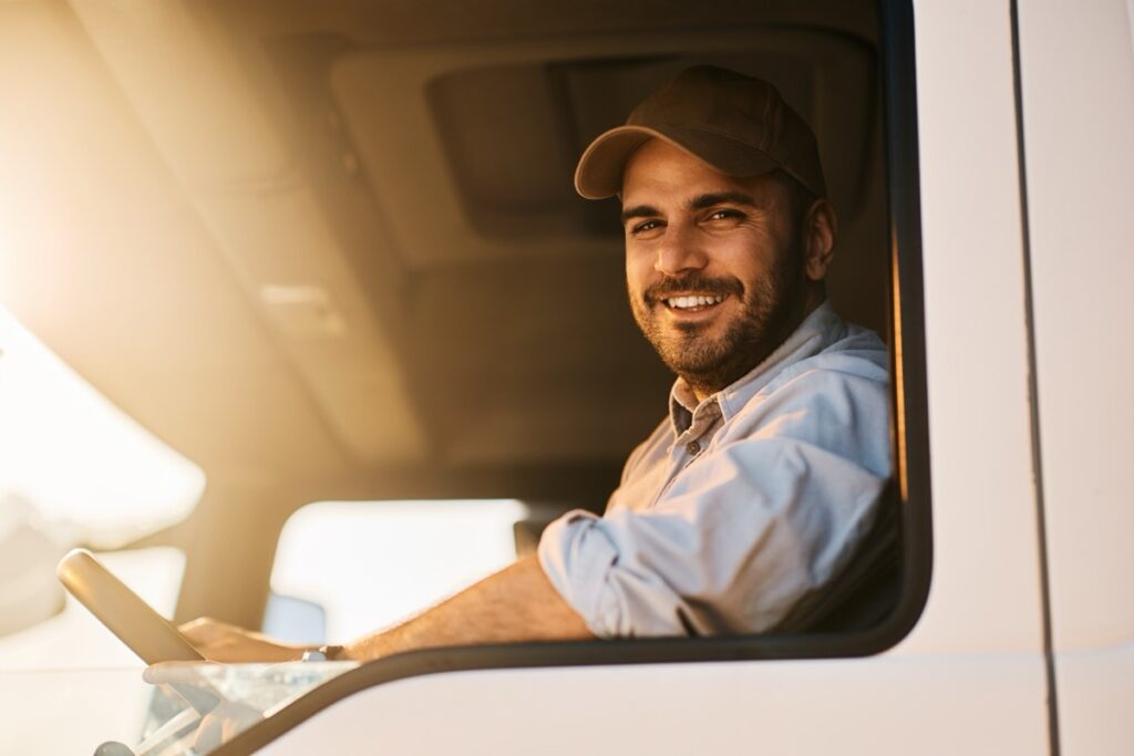 Happy,Truck,Driver,Sitting,In,Vehicle,Cabin,And,Looking,At