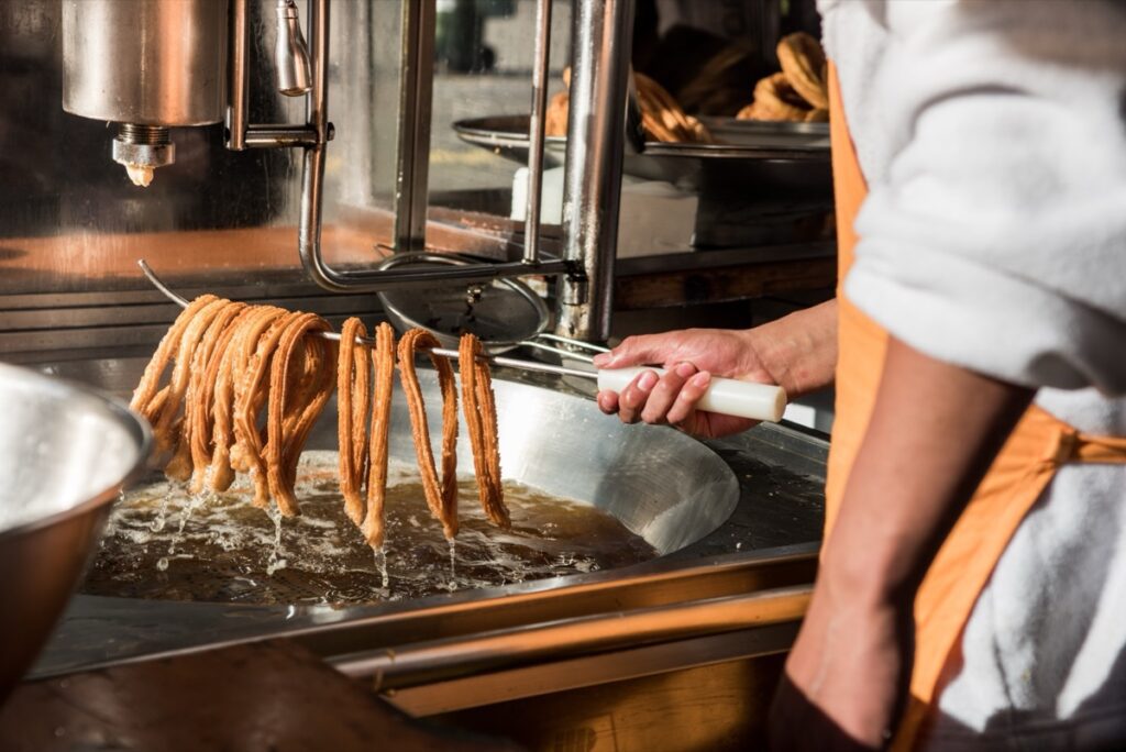 Detail,Photo,Of,A,Worker,Removing,The,Churros,From,The