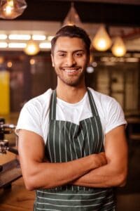 Handsome,Barista,Posing,With,Arms,Crossed,At,The,Coffee,Shop