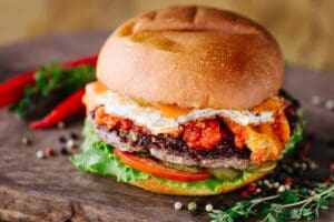 Burger With Beef, Egg, Tomato, Cheese, Lettuce and Onion. Close up