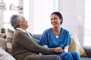 Consulting,,Caregiver,And,Elderly,Woman,Laughing,On,Sofa,And,Holding