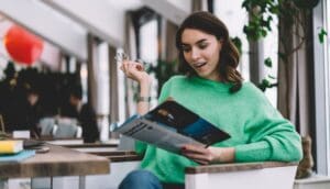 Young brunette sitting and reading magazine
